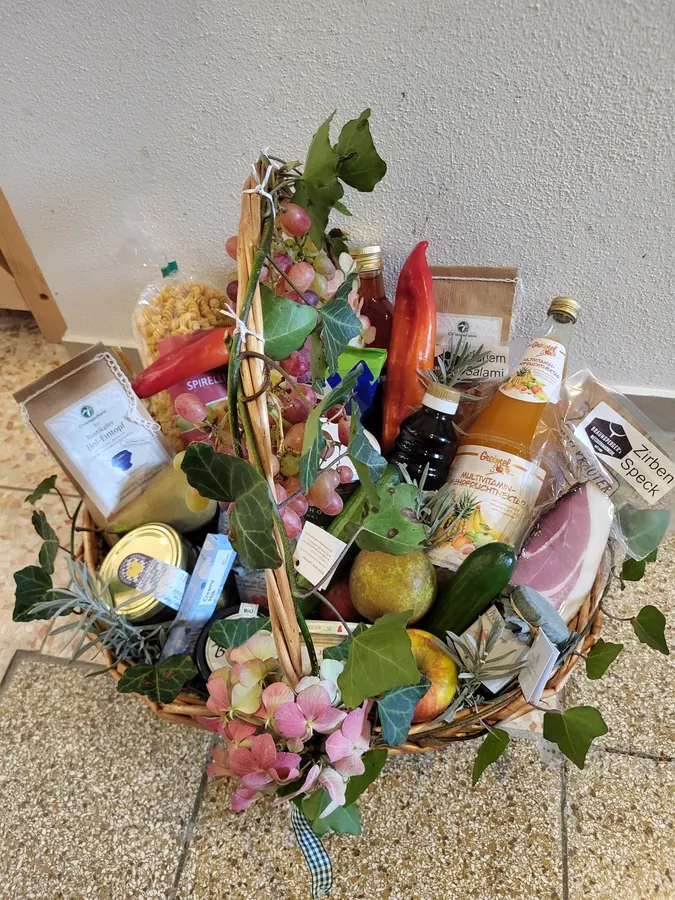 Geschenkkorb mit Blumen, Saft, Pasta, Schinken und frischem Obst
